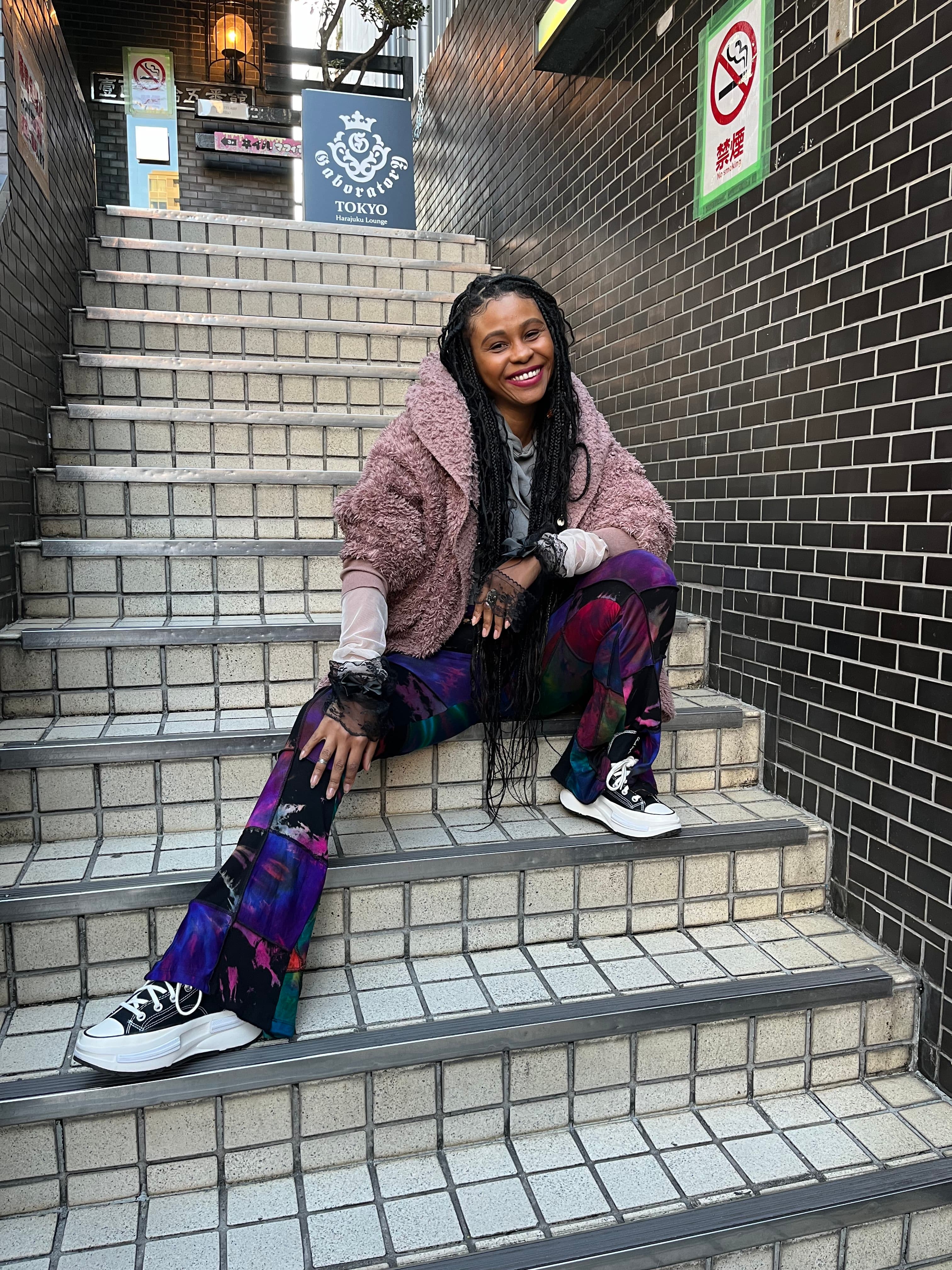 Woman sitting on staircase in colorful garments